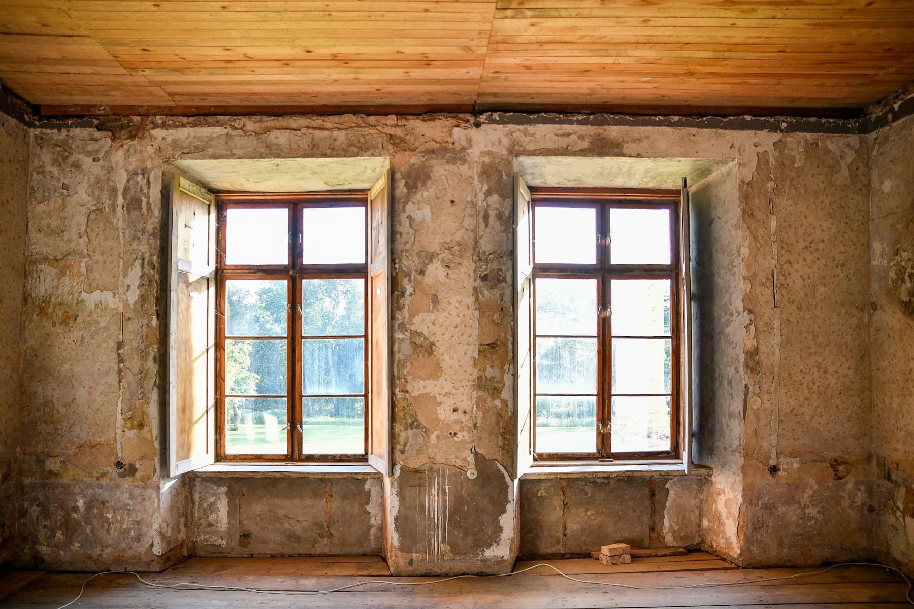 Pièce ancienne avant travaux, murs décapés et deux fenêtres