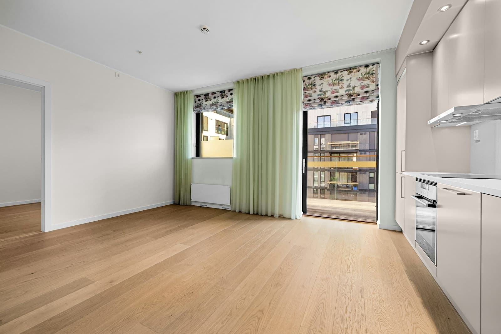 Séjour lumineux, rideaux verts et parquet clair